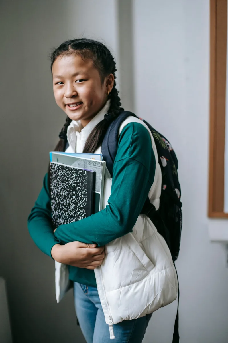 Schoolgirl holding books and wearing a backpack