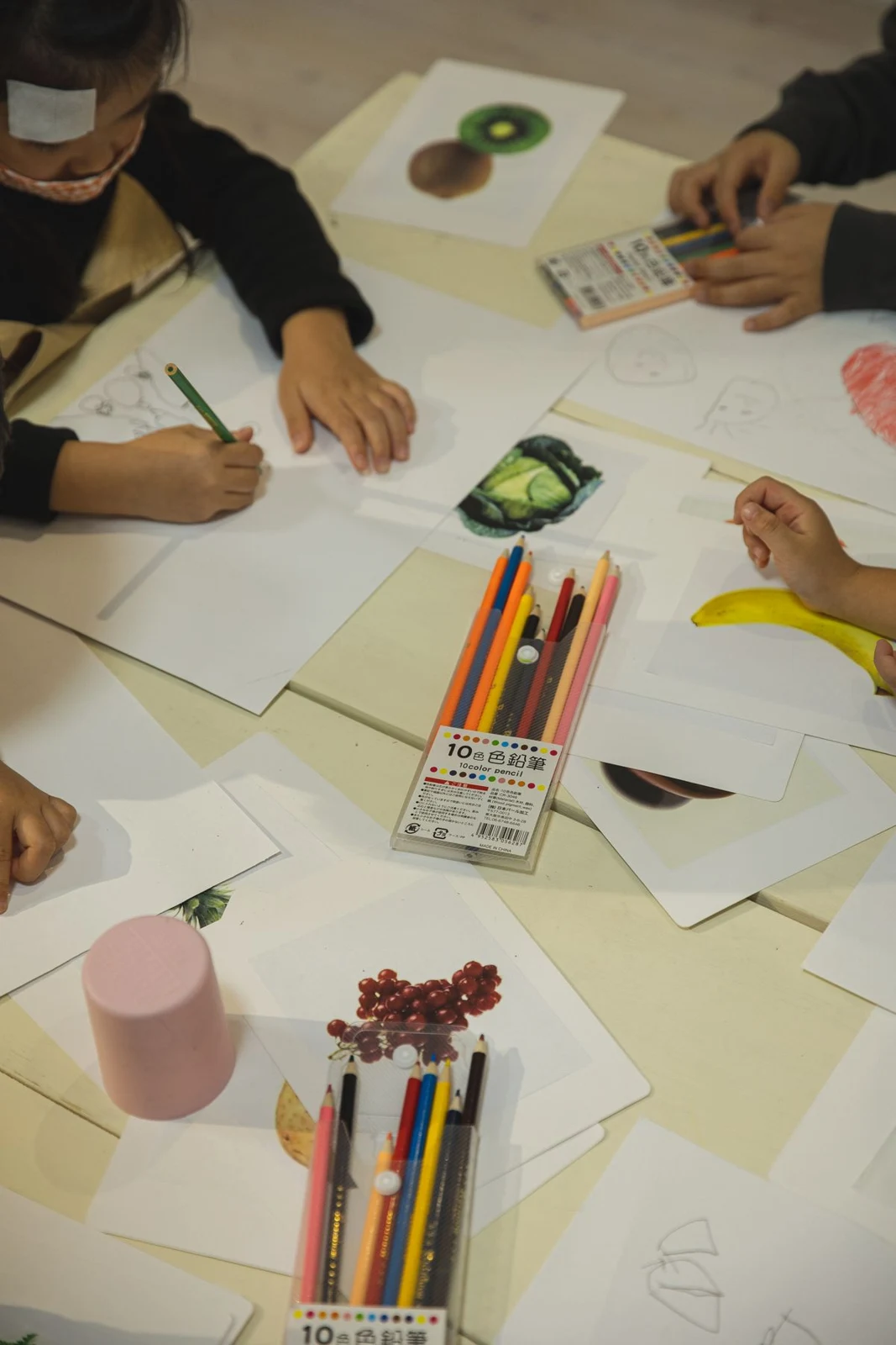 Children drawing with coloured pencils at a shared table