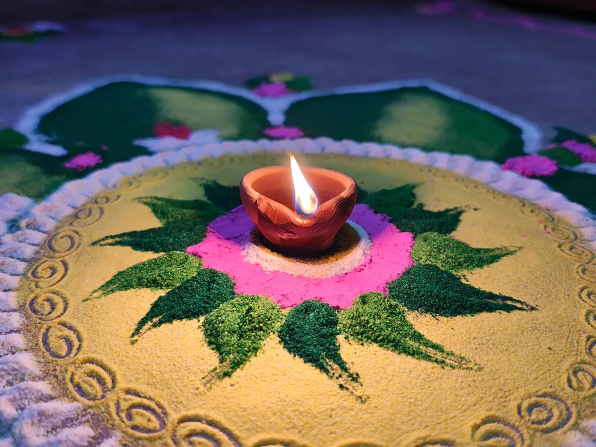 Lit clay diya on a colourful rangoli pattern