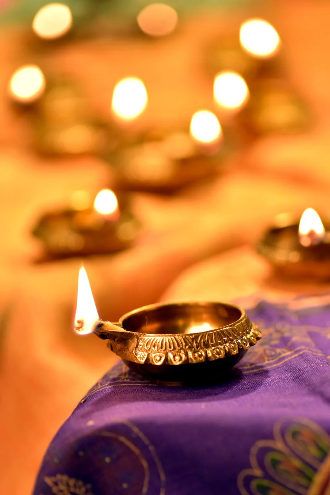 Traditional brass oil lamp with other lit lamps in the background