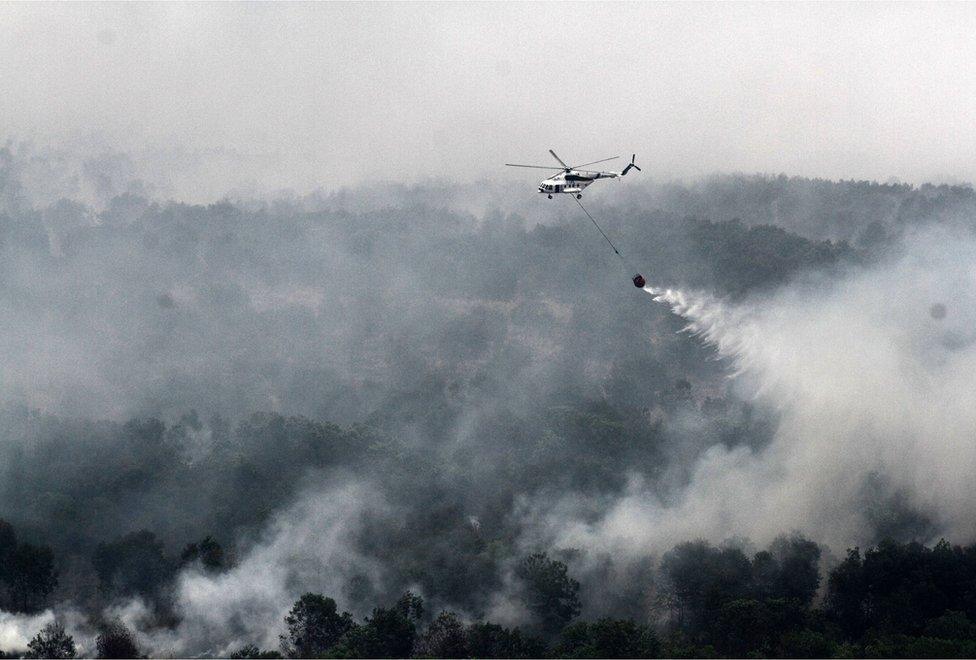 Indonesian helicopter dropping water over a forest fire in South Sumatra