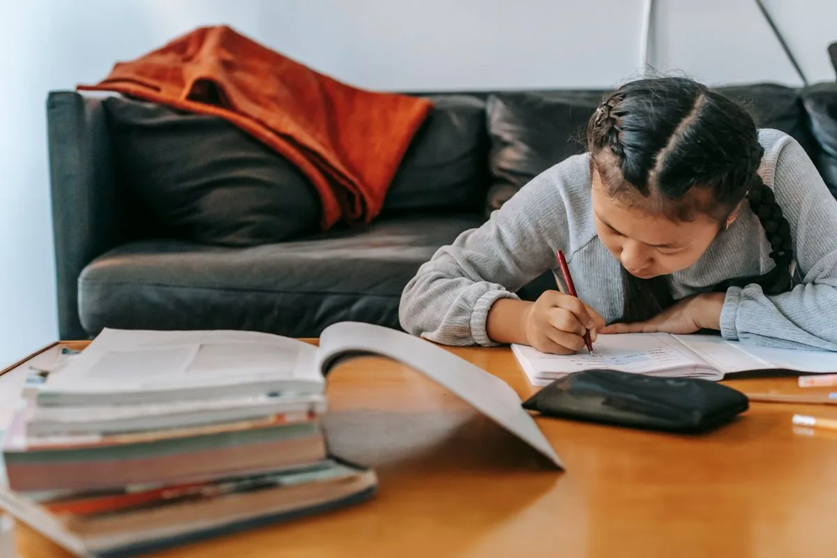 Schoolgirl writing in an exercise book at home