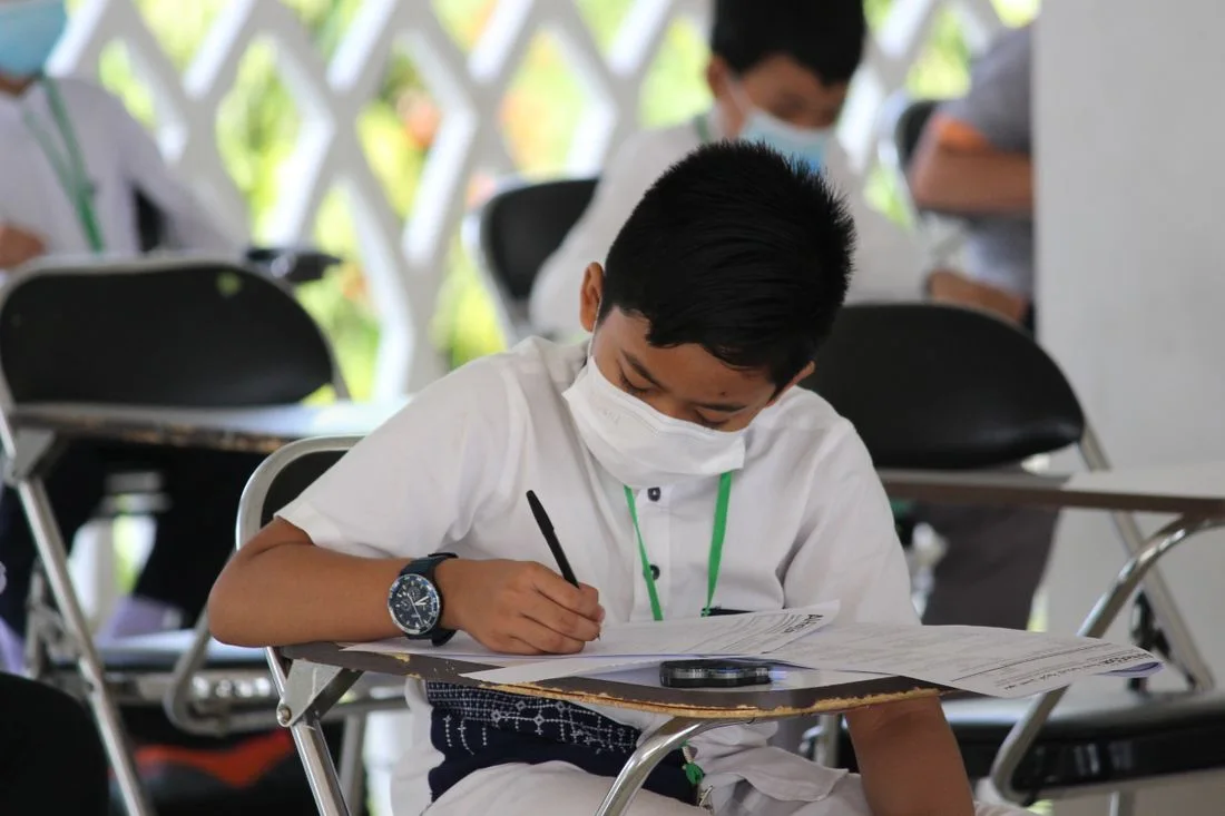 A pupil wearing a mask while completing written work