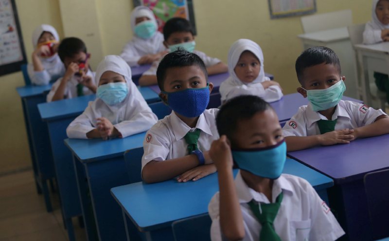 Primary school children wearing face masks while seated at classroom desks
