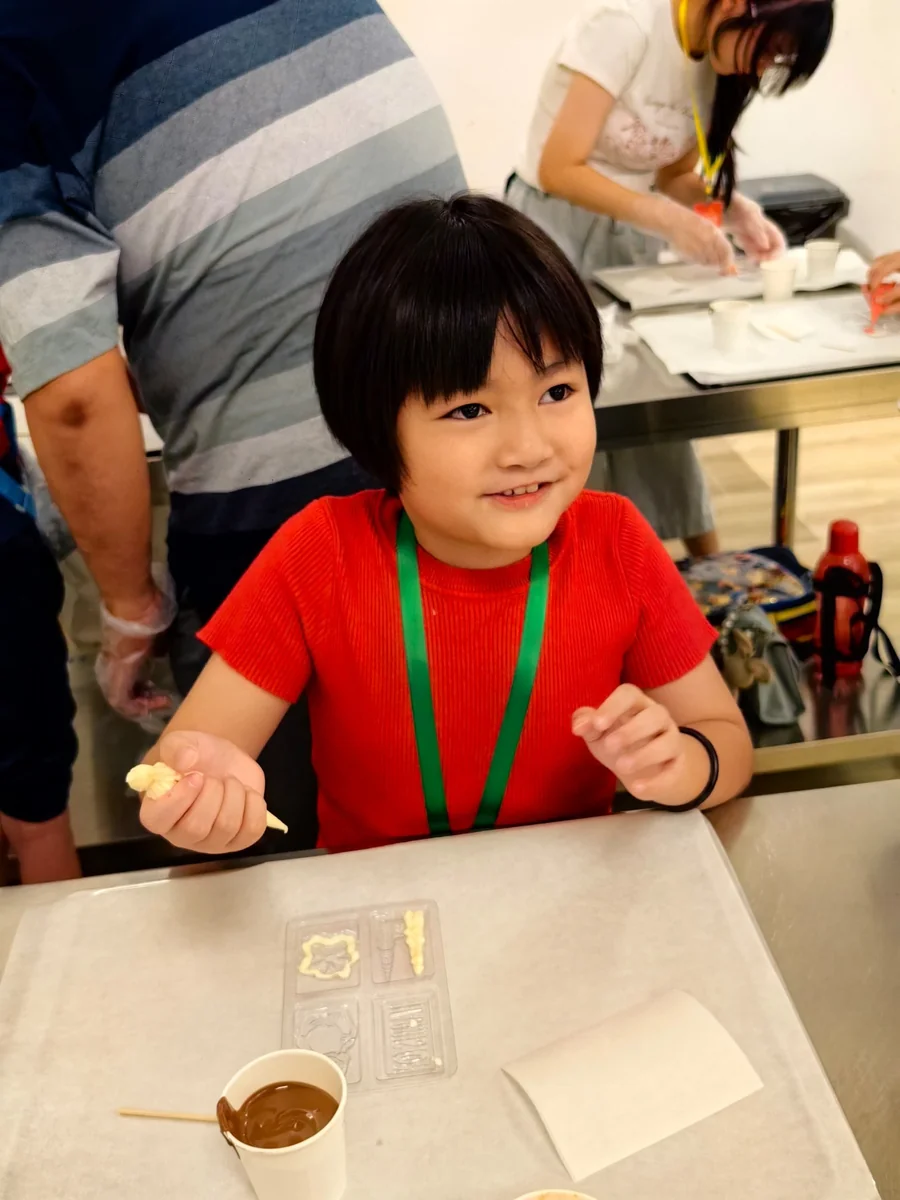 A myKiwi child filling chocolate moulds during a chocolate factory learning trip