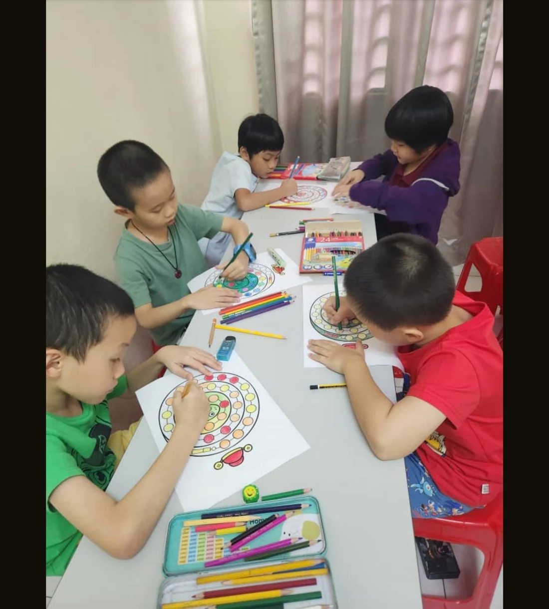 Children colouring snake crafts together at a table at myKiwi Kajang