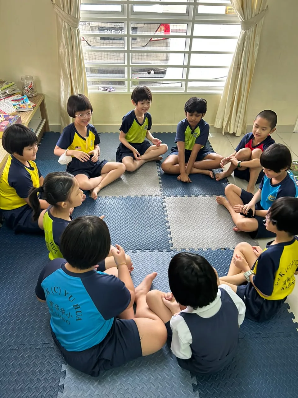 Children sitting in a circle for a group activity at myKiwi Kajang