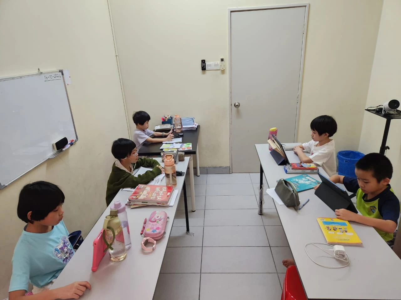 Primary school children attending online lessons on tablets at myKiwi Daycare & Tuition in Kajang