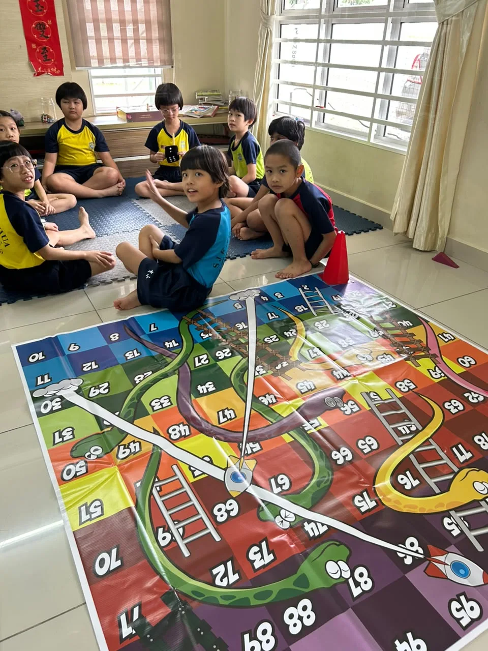 Children participating beside a snakes-and-ladders mat at myKiwi Kajang