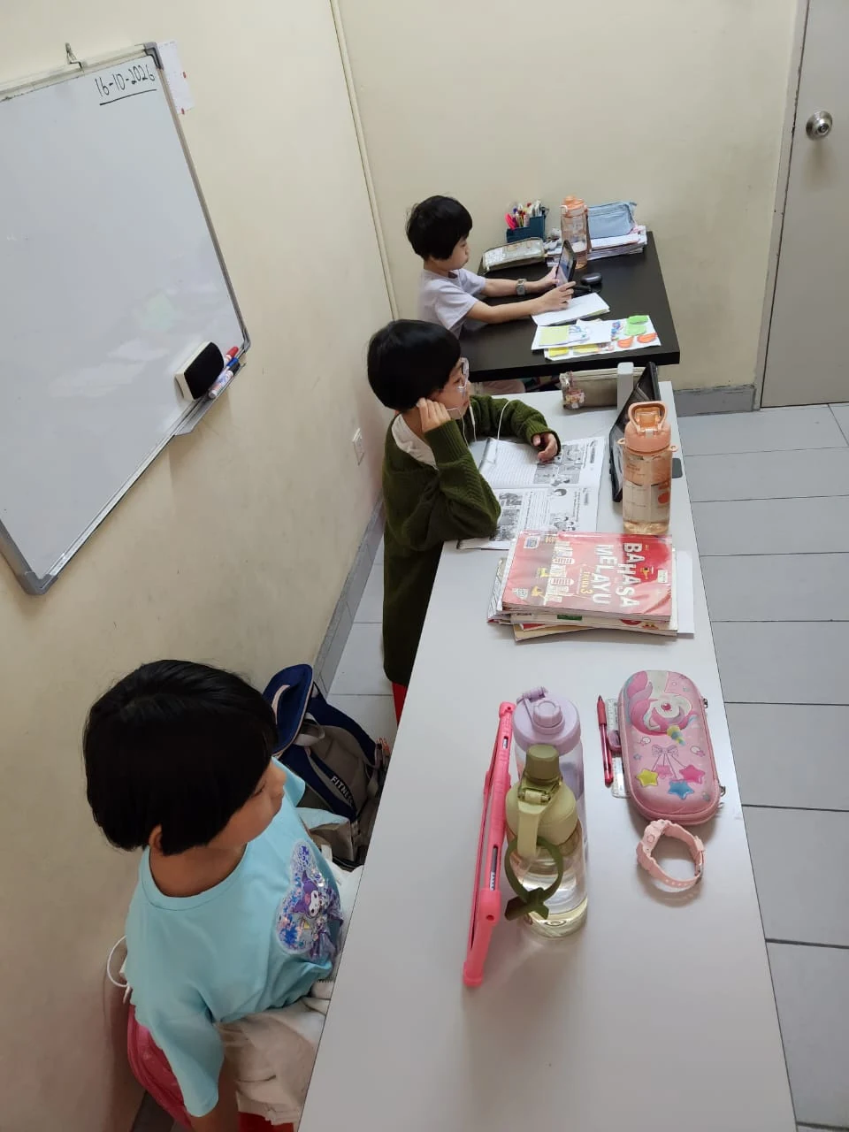 Children at myKiwi following tablet lessons with workbooks and stationery on their desks
