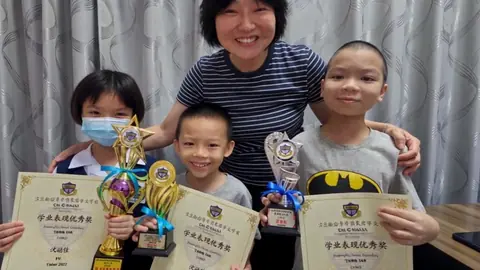 The myKiwi founder with children holding trophies and certificates