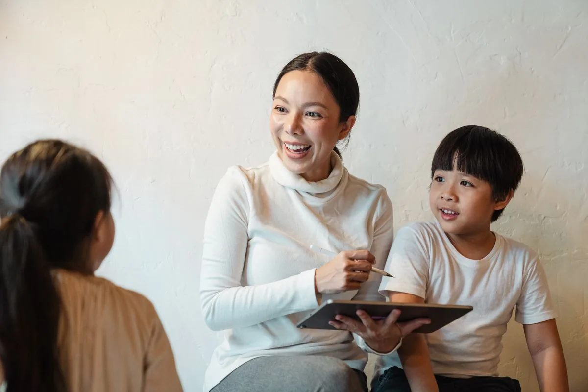 Mother talking with children while holding a tablet
