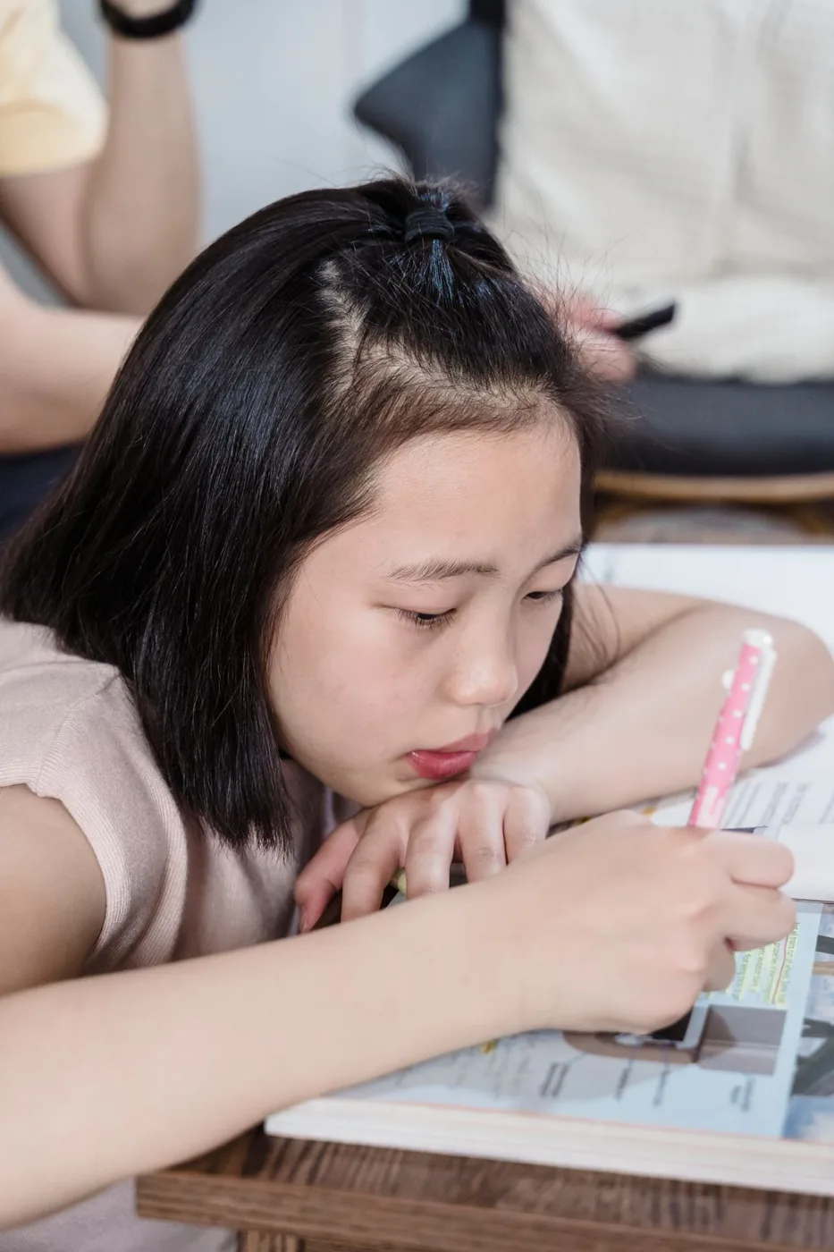 A pupil writing in a book with a pencil