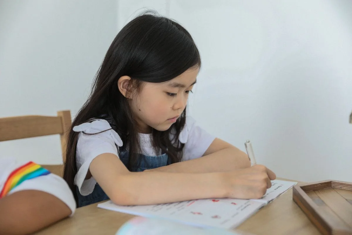 Schoolgirl working in an exercise book at a table