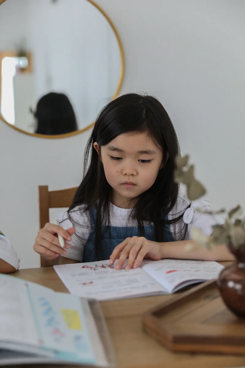 Schoolgirl concentrating on a notebook at a wooden study table