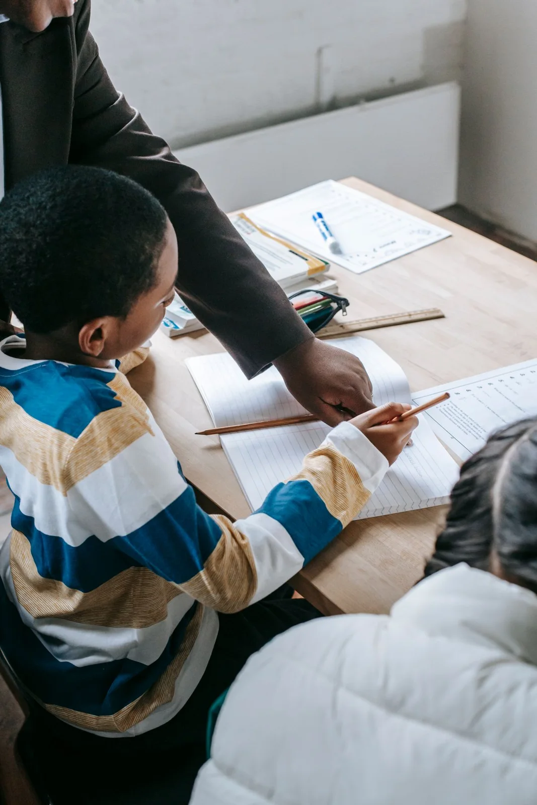Teacher guiding children with written schoolwork