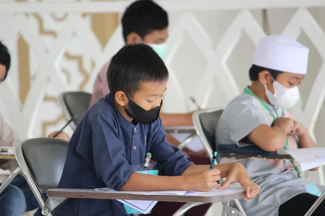 Masked pupils writing at classroom desks