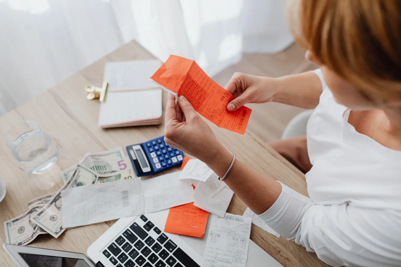 A woman checking receipts beside a calculator and notebook at a desk
